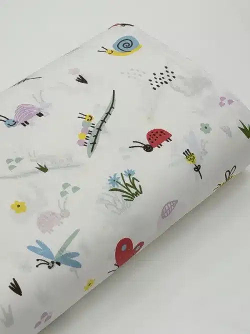 عکس واقعی پارچه پارچه کتان ترک ملحفهای بچهگانه طرح حشرات رنگی، پروانه، کفشدوزک، سنجاقک، کرم و گلهای ریز با رنگهای شاد روی زمینه روشن